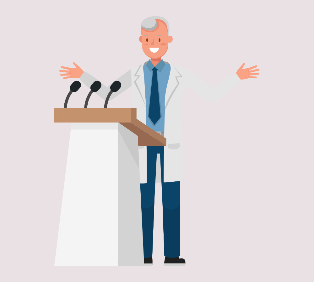 Elderly male speaker in a laboratory coat giving a speech into microphones.